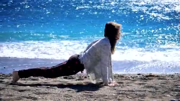 Young woman making sun salutating excercise near the sea — Stockvideo