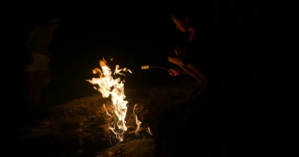 Жінка смажить зефір у вогні — стокове відео