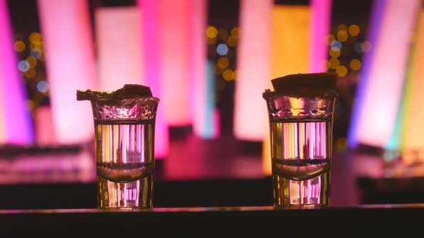 Paar nemen twee zilveren tequila shots met kalk op Bar teller met kleur veranderende LED-buislampen — Stockvideo