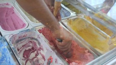 Vitrin dondurma bir dondurma dükkanında, adam bir waffle koni içine dondurma topları koyar