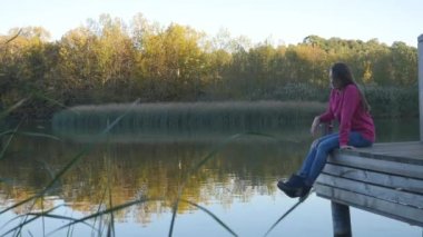 Young woman relaxes on lake pier.