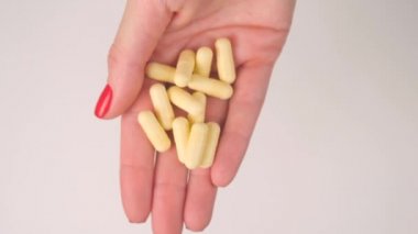 Womans hand gives yellow capsule pills