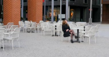 Young woman sits in outdoor cafe