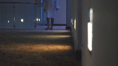 Bornoz giymiş tanınmayan kadın otel koridorunda yürüyor 