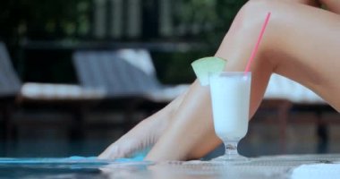 Yüzme havuzu ve kokteyl tarafından güzel kadın bacaklar