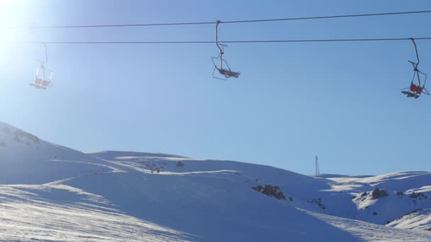 Вид движущегося подъемника и сноубордистов со снежной горы на заднем плане — стоковое видео