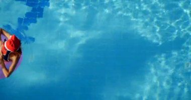 Woman in santa hat relaxing in a pool on the pink inflatable ring