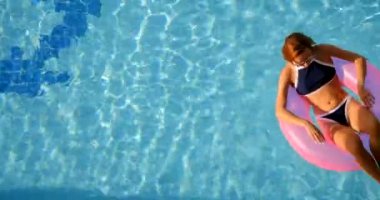 Woman relaxing in a pool on the pink inflatable ring