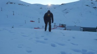 Young man in dark clothes falling down exhausted on a snowy mountain