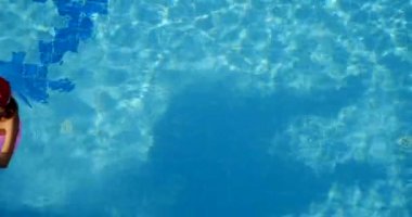 Woman in santa hat relaxing in a pool on the pink inflatable ring