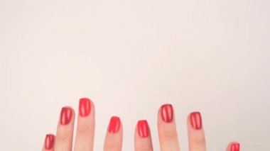 Womans hands with red manicure appear on white background