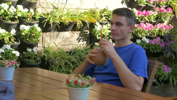 Молодой человек сидит за столом с кокосовым напитком — стоковое видео