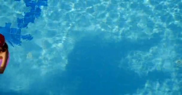 Mulher em santa chapéu relaxante em uma piscina no anel inflável rosa — Vídeo de Stock
