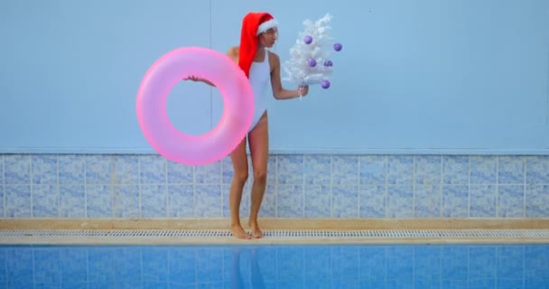 Yüzme havuzunun yanındaki Noel Baba şapkalı güzel bayan. — Stok video