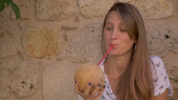 Jeune femme souriante buvant de l'eau de noix de coco — Video