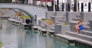 woman sitting on the stairs at the canal