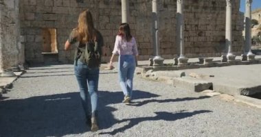 Young female tourists walking in Ancient city Perge, open air antique historical museum