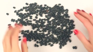 Womans hands forming heart from black beans
