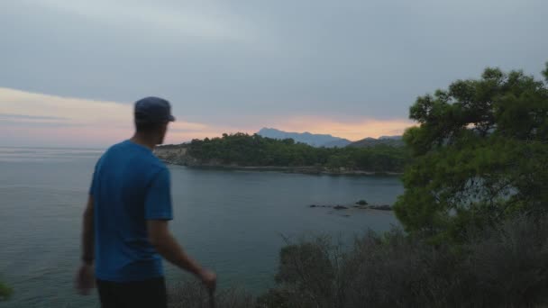 Escursionista che guarda verso il mare beatifull vista. Giovane turista che cammina lungo il sentiero sulla cima di una montagna . — Video Stock