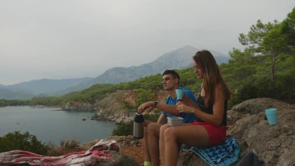 Jeune couple assis sur des rochers en forêt manger pique-nique — Video