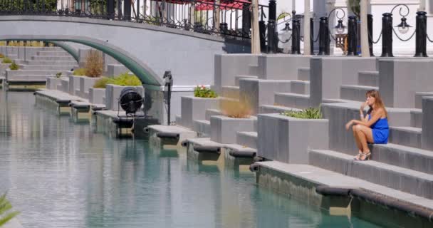 Woman sitting on the stairs at the canal — 비디오