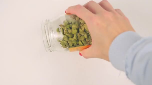 Pouring green cardamom from glass jar — Stock Video