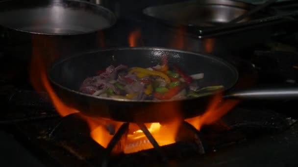 Professionell och eld. Matlagning grönsaker och mat över en öppen eld på en mörk bakgrund — Stockvideo