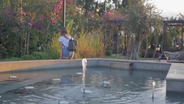 Молода жінка в літньому повсякденному одязі, що йде сама в парку — стокове відео