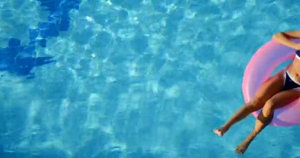 Mulher em santa chapéu relaxante em uma piscina no anel inflável rosa — Vídeo de Stock