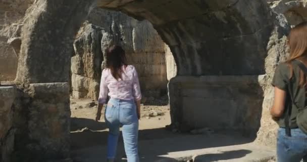 Jóvenes turistas femeninos caminando en la ciudad antigua Perge, museo histórico antiguo al aire libre — Vídeos de Stock