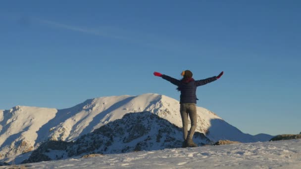 Νεαρή γυναίκα γυρίζει γύρω από τον ουρανό και τα βουνά του χειμώνα — Αρχείο Βίντεο
