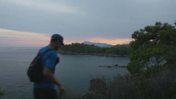 Η οικογένεια κοιτάζει την αγιοπλήρη θέα στη θάλασσα το ηλιοβασίλεμα. Οικογενειακός τουρίστας με σακίδια που περπατούν στην κορυφή ενός βουνού. — Αρχείο Βίντεο