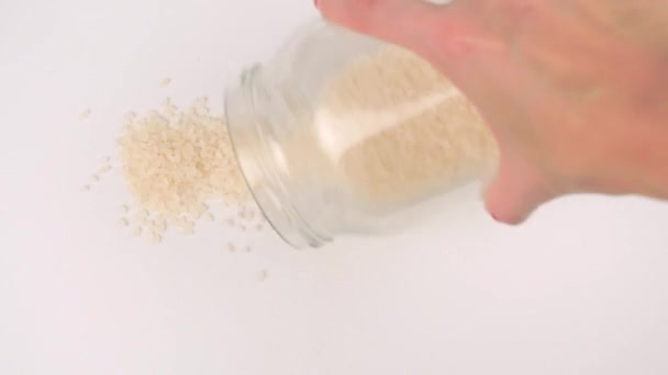 Выливание белых семян риса из стеклянной банки — стоковое видео