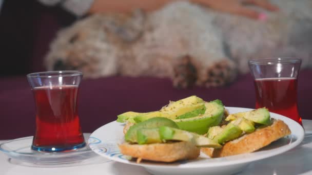 Las mujeres desayunan con sándwiches de aguacate y té rojo — Vídeos de Stock