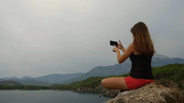 Γυναικείος τουρίστας κάθεται σε ένα βράχο σε καθαρό ουρανό και ήρεμη θάλασσα φόντο — Φωτογραφία Αρχείου