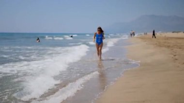 Young woman running down the sandy beach.
