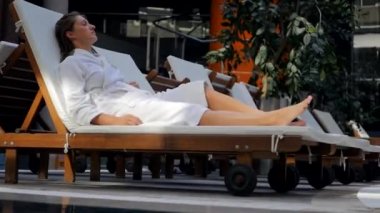 Young woman in bathrobe on the sunbed intdoors