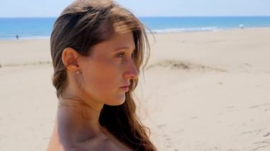 Young beautiful woman standing on sand dunes near the sea.