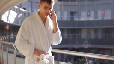 Bornozlu genç adam cep telefonuyla konuşuyor.