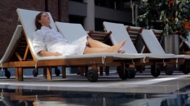 Young woman in bathrobe on the sunbed intdoors