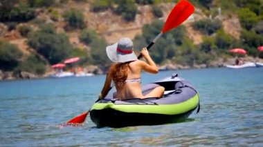 Genç bir kadın denizde kayak yapıyor..