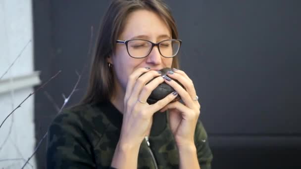 Menina comendo hambúrguer preto . — Vídeo de Stock