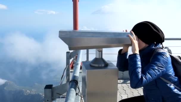 Young woman looking through telescope at viewpoint in the mountains — Stockvideo