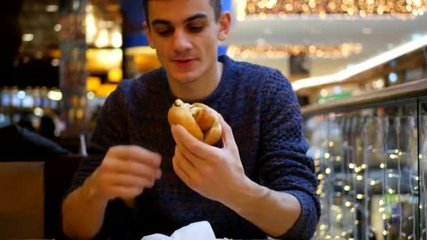 Молодой красивый мужчина ест хот-дог — стоковое видео
