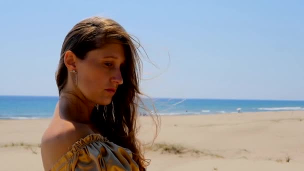 Young beautiful woman standing on sand dunes near the sea. — Stok video