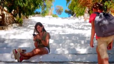Young woman with boy sitting on stairs looking at smartphone