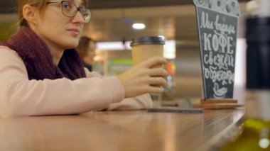 Woman hand with paper cup of coffee using smartphone