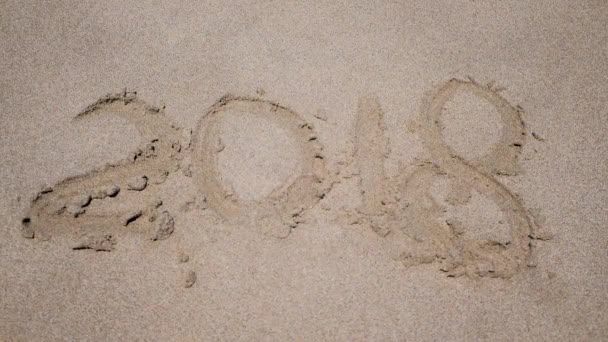 Welle spült Jahr 2018 handschriftlich am Sandstrand weg. — Stockvideo
