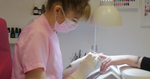 Vrouwelijke manicure verwijdert oude gel van klanten nagels. — Stockvideo