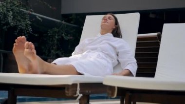 Young woman in bathrobe on the sunbed intdoors